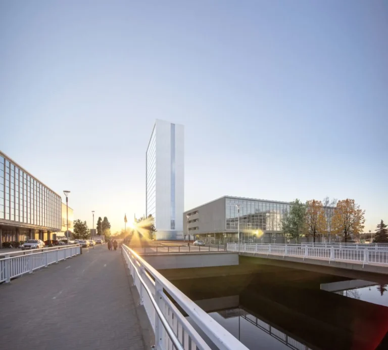 Havainnekuva tornihotellista kauempaa katsottuna. Matalalla paistava aurinko paistaa hotellin kulmasta.